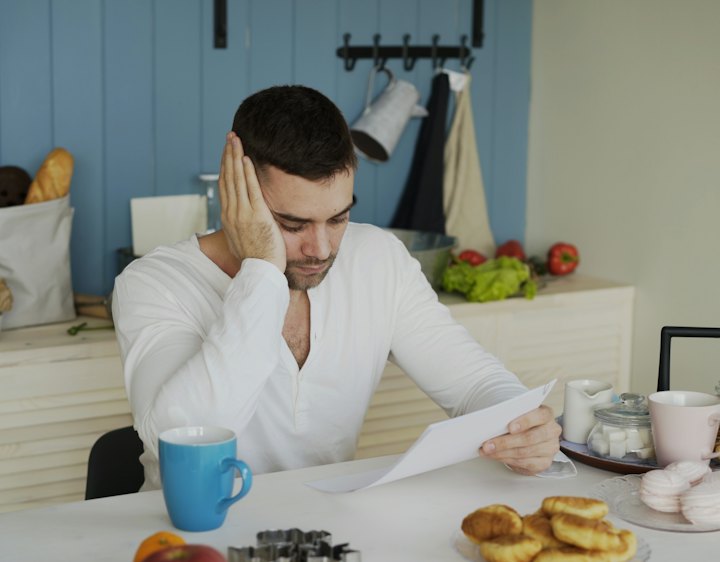 A man reading a tax document at his kitchen table