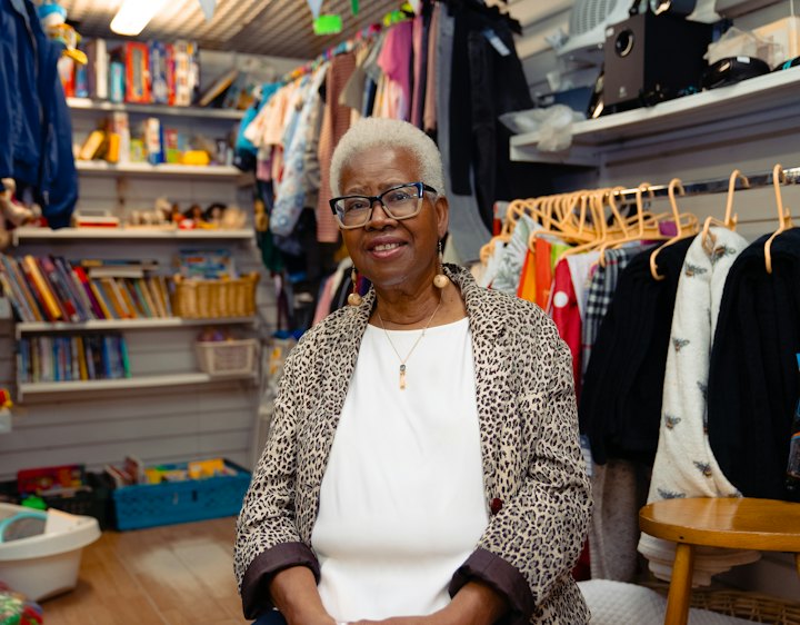 Owner of a small clothing shop sitting among her stock